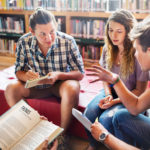 Students discussing a book in library