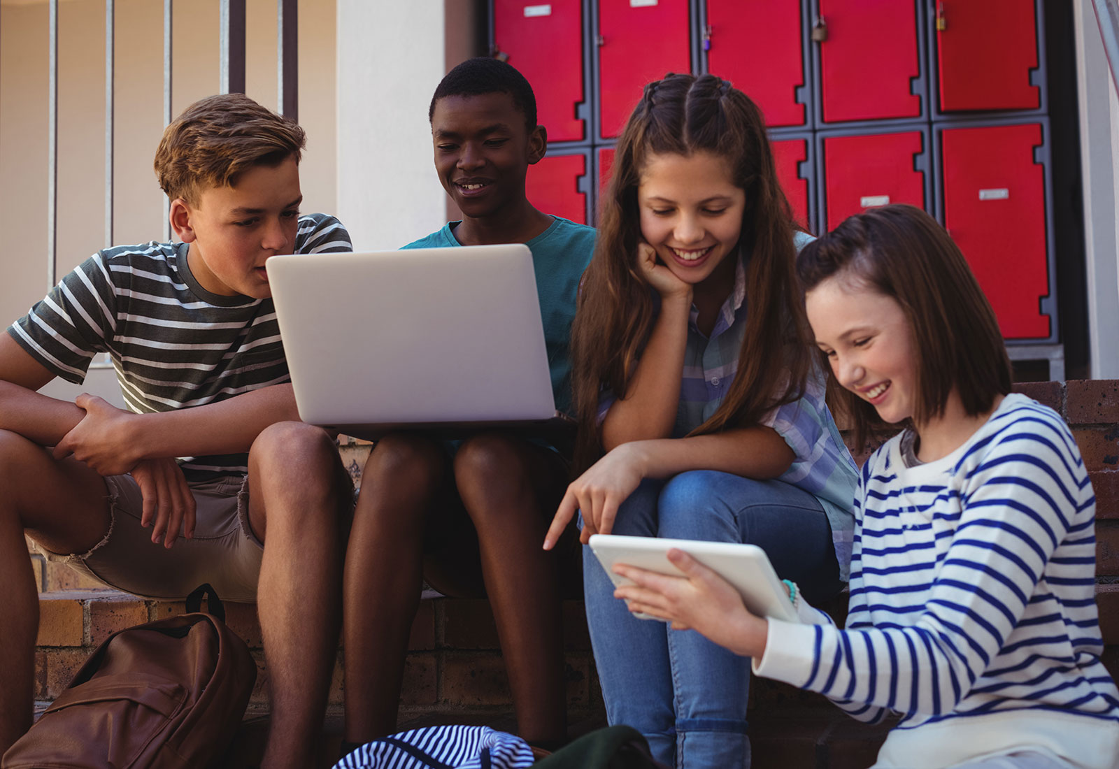 Students Using Computers Outside Red Lockers