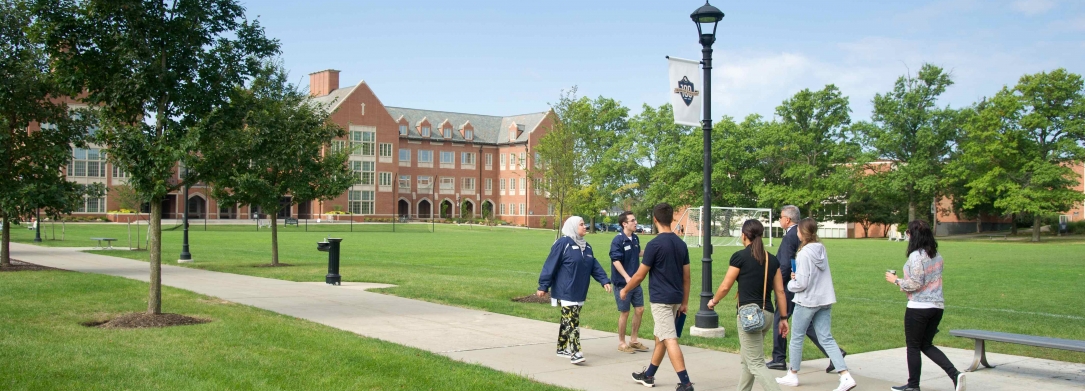 John Carroll University campus lawn and building with students strolling on pathway
