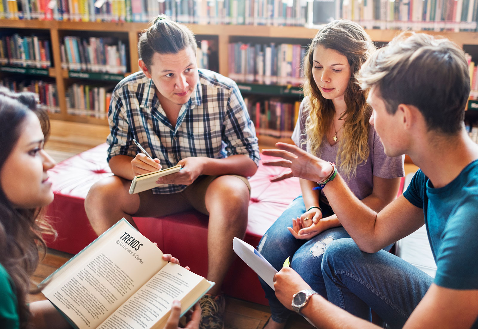 Students discussing a book in library