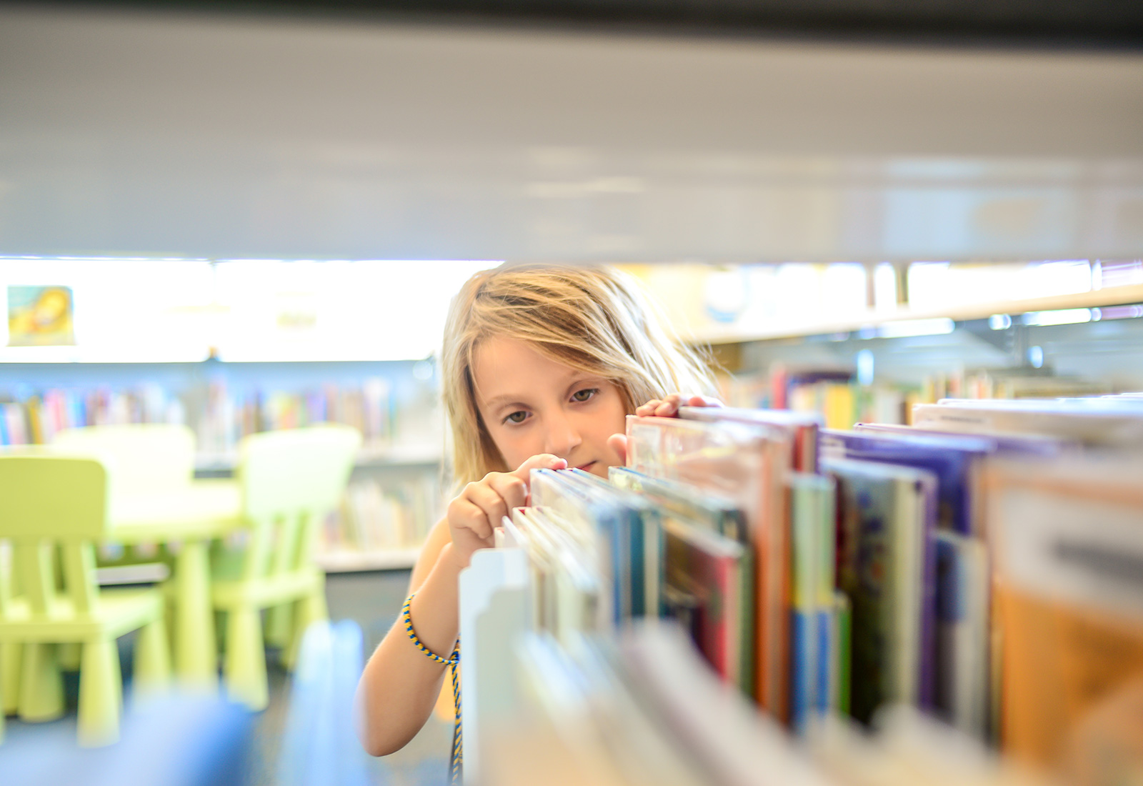 Child looking though bookshelf